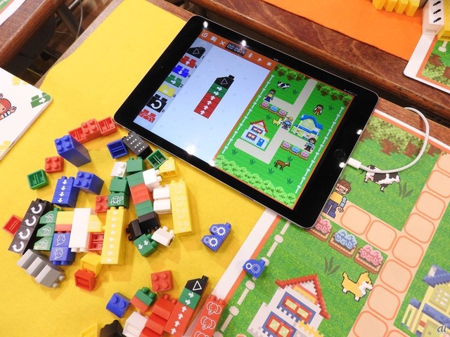 　3歳から学べるプログラミング可能な子どもブロック。ブロックをつなげて、アプリでも同じように画面でブロックをつなぐと、人形がブロックにそって動いてくれる。プログラミングでキャラクターを動かしながら、各ステージのミッションに挑戦できるという。