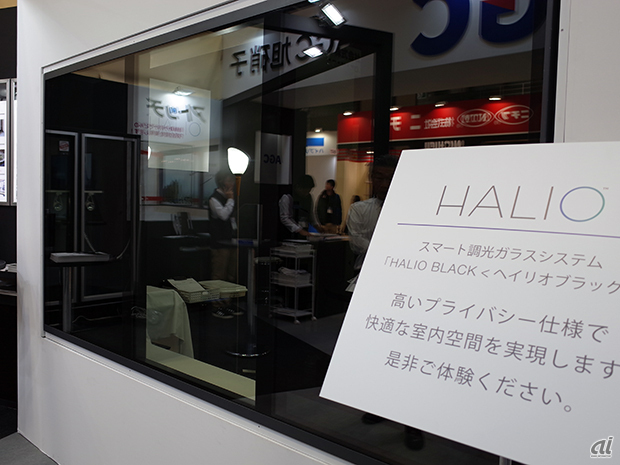 　AGC 旭硝子では、スマート調光ガラス「Halio（ヘイリオ）」を出品。写真は可視光線を最大99.9％遮断できるという「Halio Black」。中央の部分が「クリアステージ」で左右の部分が「ダークステージ」になる。

　2枚のガラスの間に化学材料をはさみ、そこに電気を通すことで、ガラスの色が変わる仕組みで、ブラインドやカーテンなしに過ごせるとのことだ。