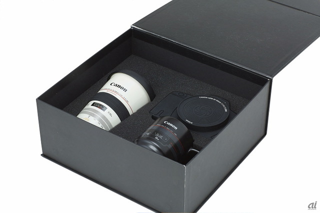 　プレミアムギフトボックス「MC-MUG SET」。オンラインショップ販売価格は5800円（税別）。レンズマグMC-MG001とMC-MG002、カメラ型のシリコン製コースターを高級感のある化粧箱に収めたもの。シリコン製コースターは、カメラのレンズ部分も別途2枚のコースターとして使用できる、ギフトボックス専用の商品。メッセージカードも同梱されており、贈答用にメッセージを書き込める。
