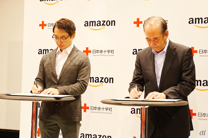 調印式でサインする、アマゾンジャパン社長のジャスパー・チャン氏（左）と日本赤十字社 副社長の大塚義治氏（右）