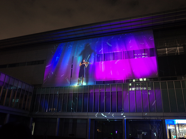 品川にいるバイオリニスト依田彩さんの演奏と映像が有明にあるパナソニックセンターの壁に浮かび上がる