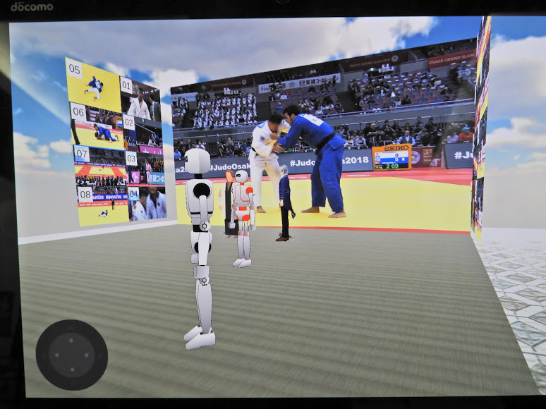 VR空間内には試合中継の大きいスクリーンと両脇に16台のカメラ映像がサムネイルで表示される
