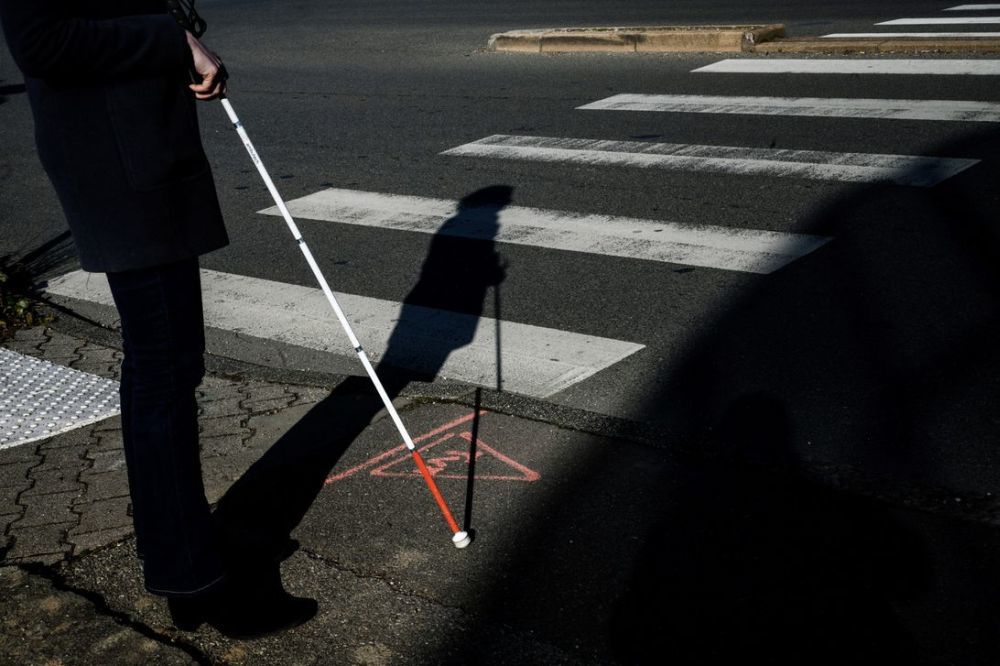 杖を持って横断歩道を渡ろうとする人の写真