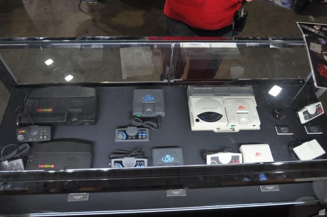 　ショーケースに展示された各種ゲーム機本体。奥側（上部）がオリジナル版の本体、手前（下部）が復刻した“mini”の本体となる。右側にはPCエンジン miniの周辺機器も展示。