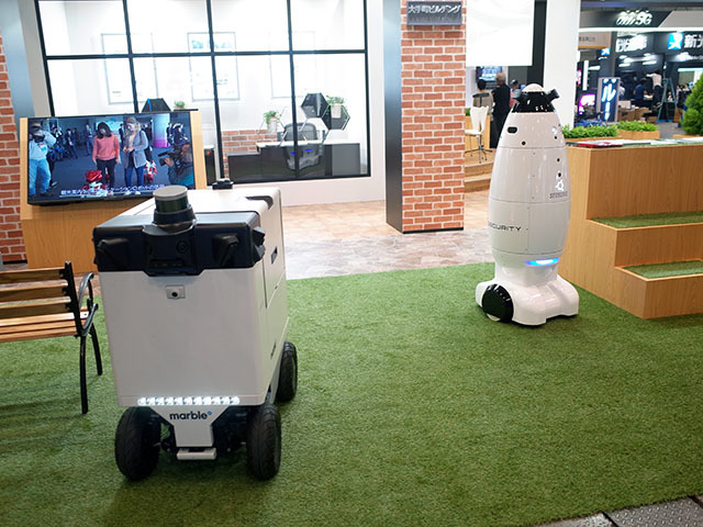 　三菱地所は、実導入済、実証実験済の複数ロボットを動態展示。左は自動運搬ロボット「Marble」で、立命館大学のキャンパス内や、大手町パークビル周辺で実証実験を実施したとのこと。右の自律移動警備ロボット「SQ-2」は、大手町パークビルティングで8月に実導入されている。
