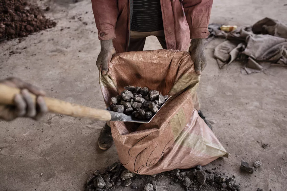 コンゴ民主共和国の採鉱場でコバルトを袋に詰める採掘者