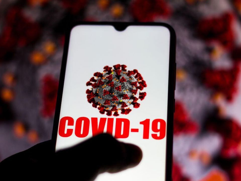 「COVID-19」の表示が浮かんだスマートフォン画面