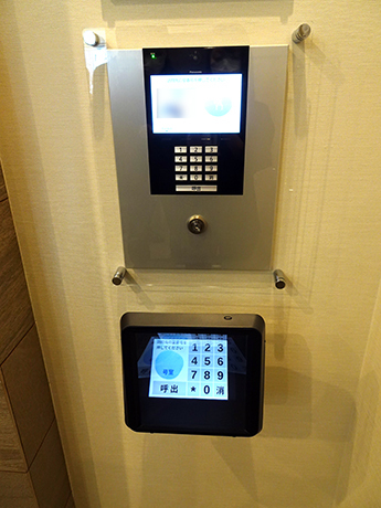 「プレミスト津田山」のマンションサロンエントランスには、通常のボタン式のインターフォン（上）と空中タッチインターホン（下）を併設する