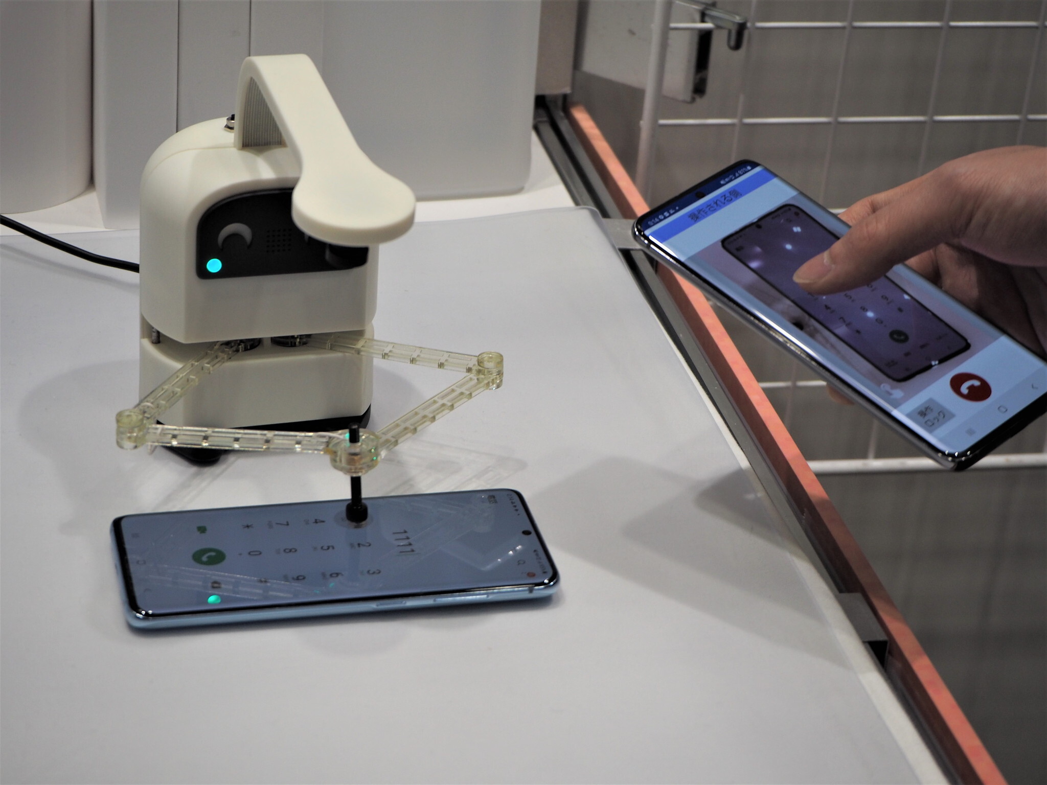 ユカイ工学と開発を進めている、スマートフォン操作支援ロボット。相手のスマートフォンを遠隔で操作すると、その操作をロボットが反映してくれるというもので、シニアのスマートフォン操作支援などの活用が見込まれている