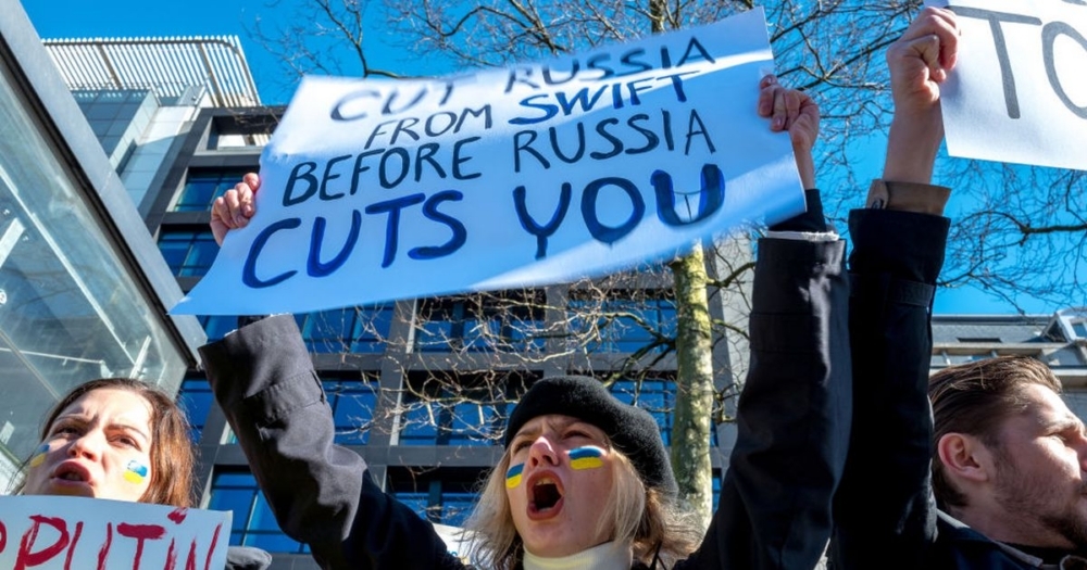 A protester holds a banner calling for Russia to be banned from the SWIFT banking system