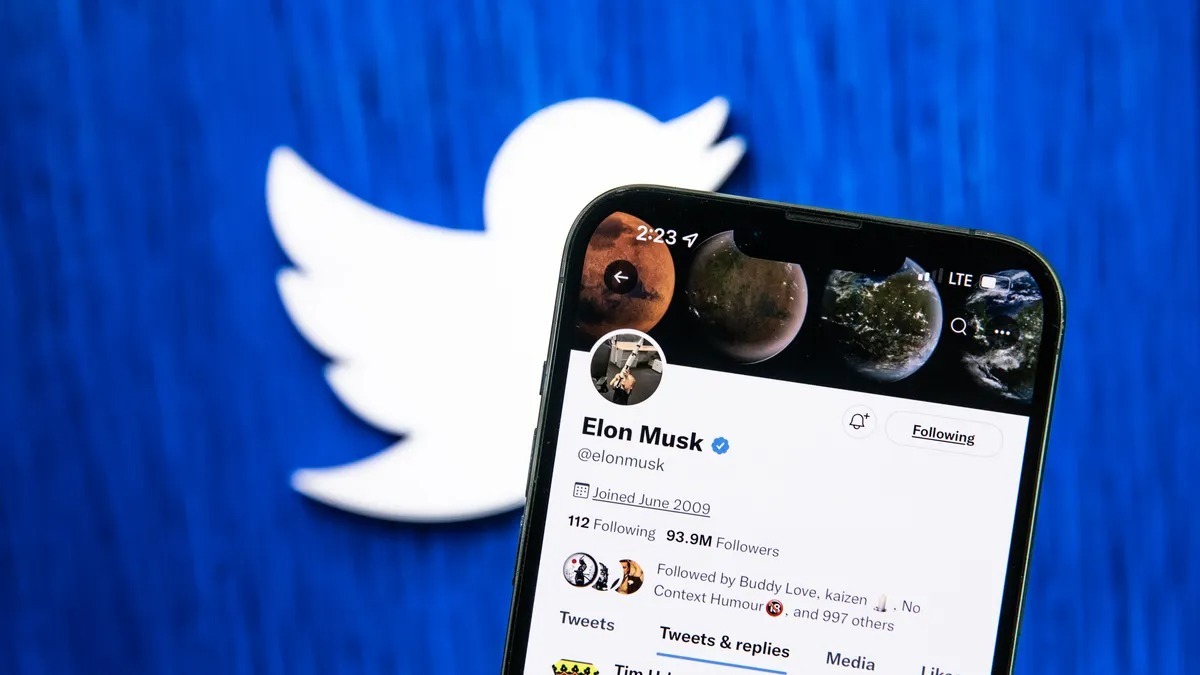 E・Musk氏のTwitterアカウントが表示されたスマートフォンと背景にTwitterのロゴ