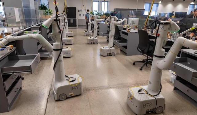 　8台のロボットが、引き出しの開閉や物体の取り上げ訓練をしているところ。
