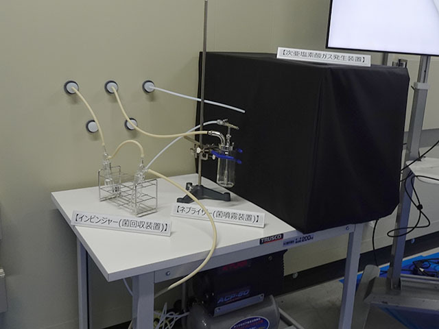試験室の前には次亜塩素酸ガス発生装置とともに、「ネブライザー（菌噴射装置）」、「インピンジャー（菌回収装置）」が設置されていた