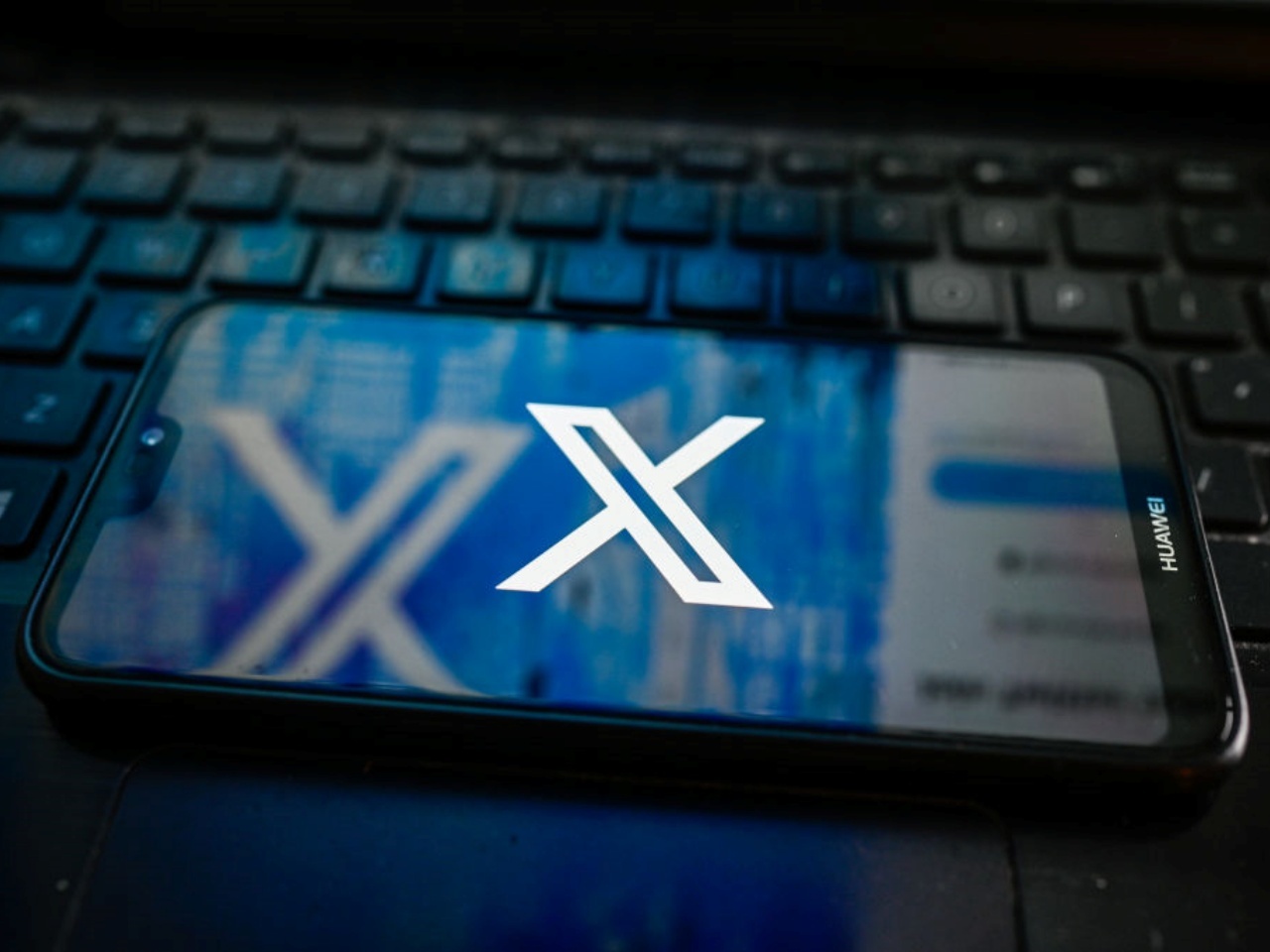 Xのロゴを表示したスマホ