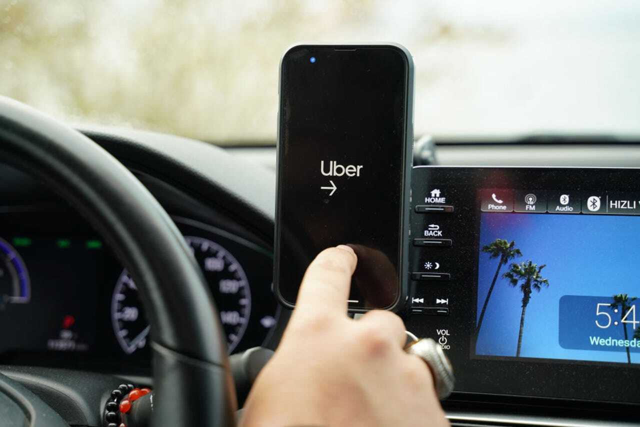 Uberと表示されたスマートフォンを車内で操作する様子