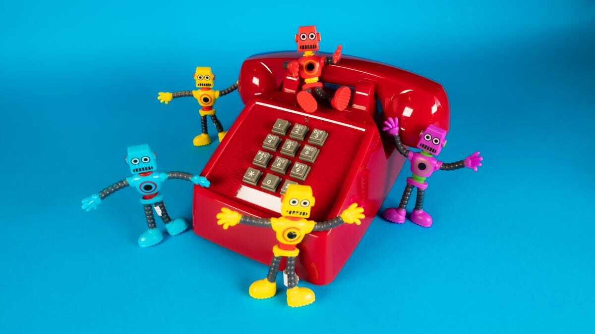 電話機の周りにロボットの玩具が5つ置かれた様子