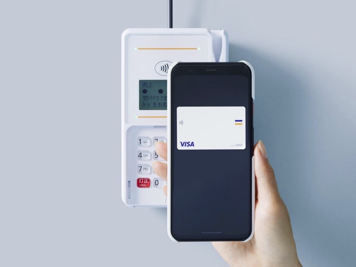 スマートフォンに登録したクレジットカードでタッチ決済する様子
