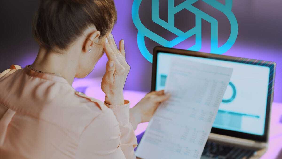 PCの前で紙の文書を見ながら悩む人物